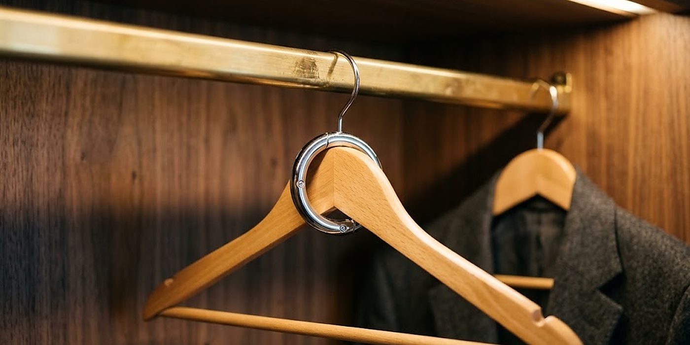 Percha de madera con anillo antirrobo cromado en una barra fija de latón, primer plano