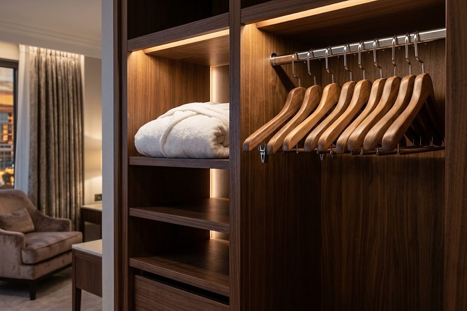 Armario abierto de una suite de hotel con perchas de madera y un albornoz doblado