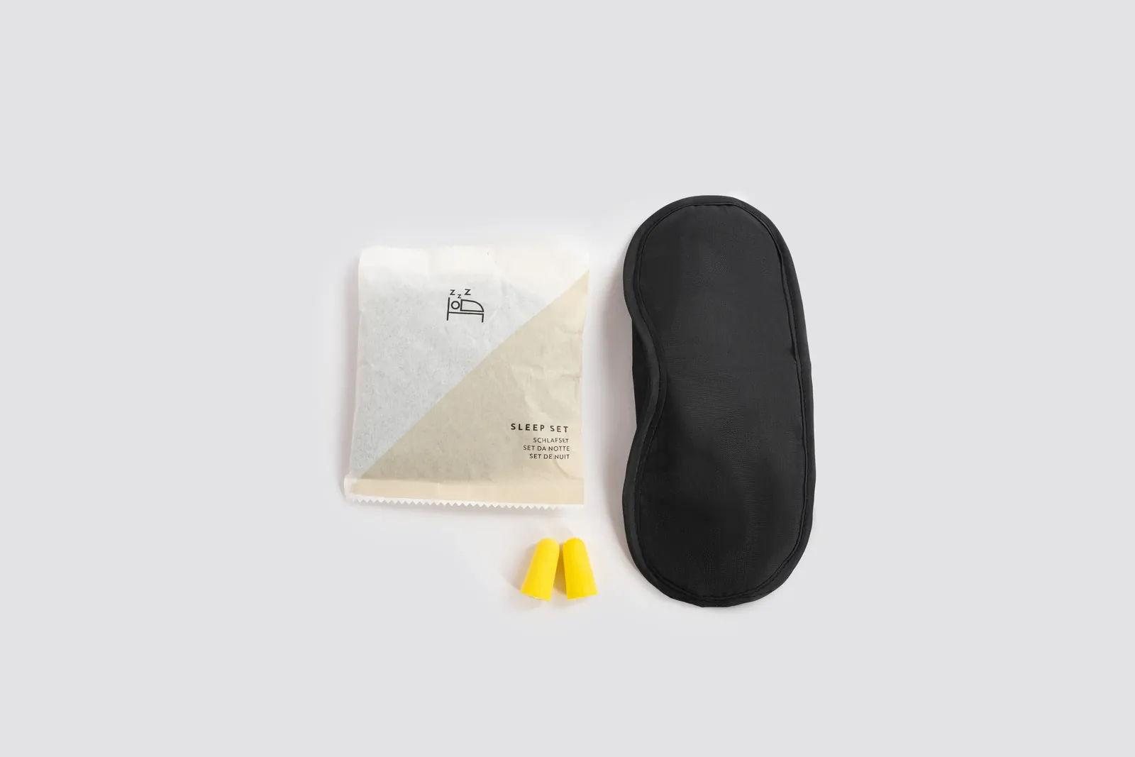 Set para dormir en sobre de papel con antifaz negro y tapones amarillos