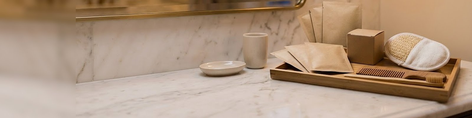 Plateau d'accueil en bambou avec sachets papier et éponge loofah dans la salle de bain d'une suite
